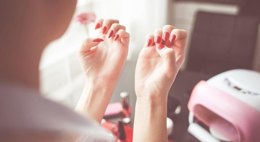 Les étapes de pose du vernis semi-permanent. Vernis rouge, manucure, ongles.